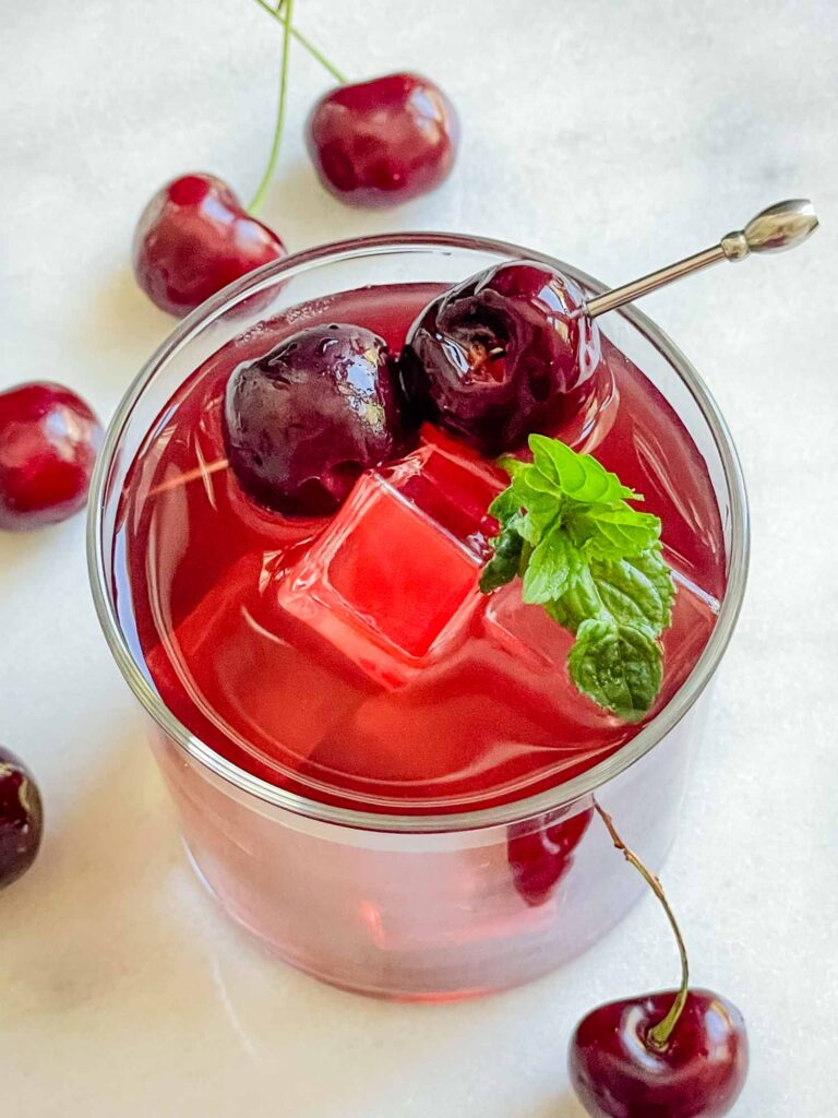 Top view of a Cherry Vodka Cocktail with brandied cherries and a mint sprig