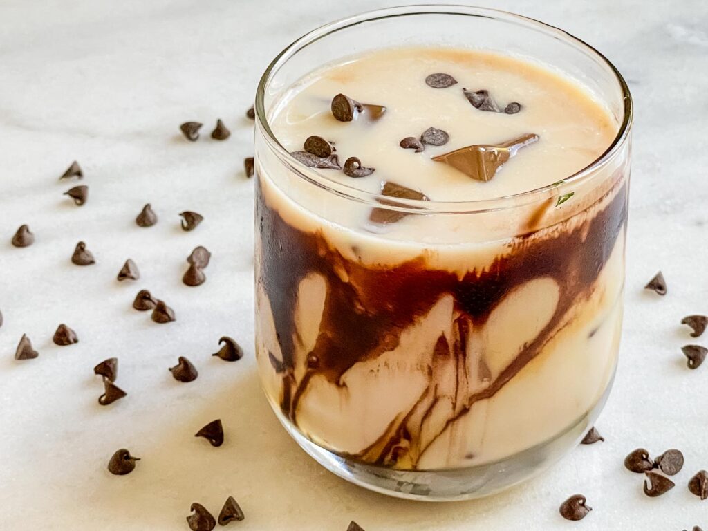 Snickers Vodka Cocktail on a white counter with mini chocolate chips around it