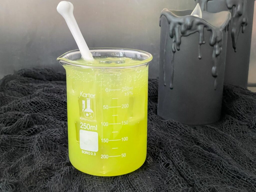A beaker full of a bright green vodka Toxic Waste Cocktail
