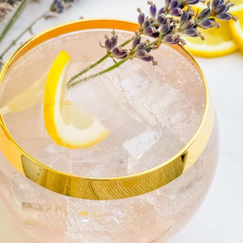 Close view of a Lavender Field Mocktail in a glass with lemon and flower garnish