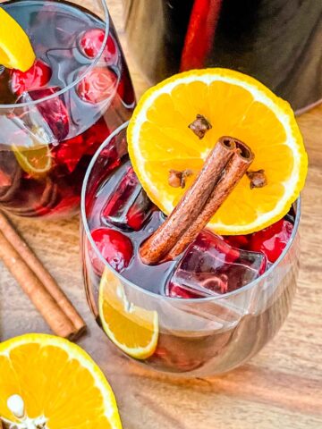 Looking down on a glass of Cranberry Orange Red Wine Holiday Sangria with an orange slice and cinnamon stick in it.