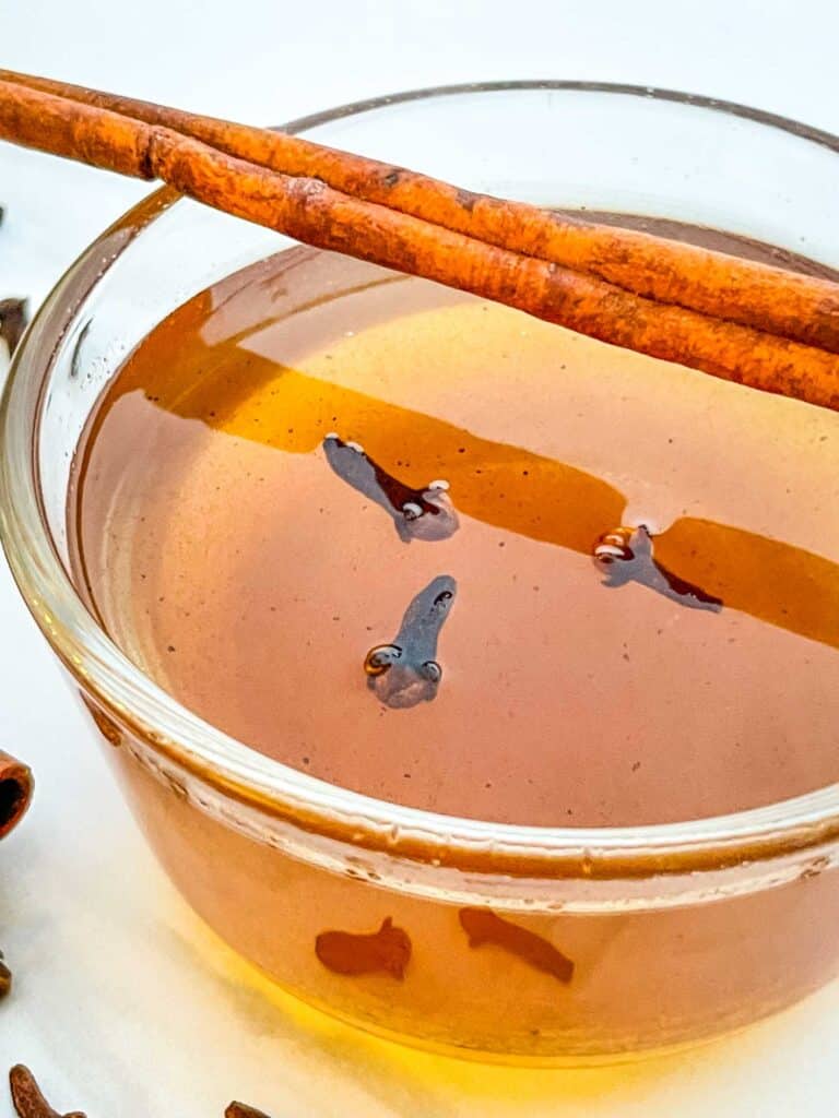 Close view of Spiced Simple Syrup in a clear jar with whole spices in it.