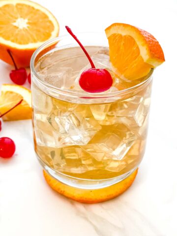 A glass of Easy Amaretto Sour Recipe with Sour Mix on a counter with fruit garnish.