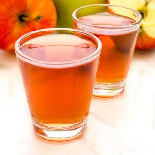 Closer view of two Washington Apple Shots on a counter with apples behind them.