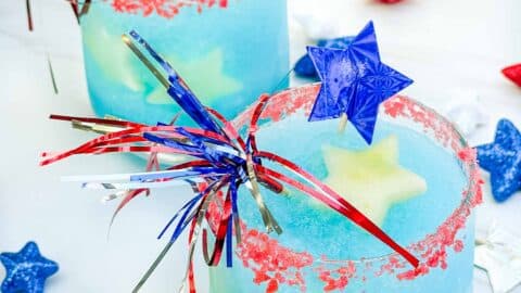 Two glasses of frozen Firecracker Margarita. Blue cocktail with white fruit stars and red rims.